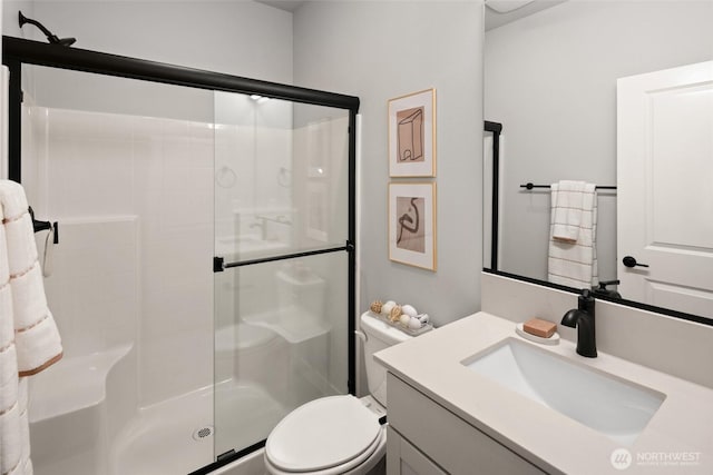 full bath featuring a stall shower, vanity, and toilet