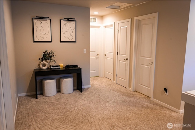 hall featuring visible vents, baseboards, and light colored carpet