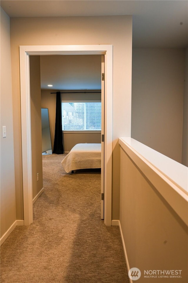 hallway with carpet flooring and baseboards