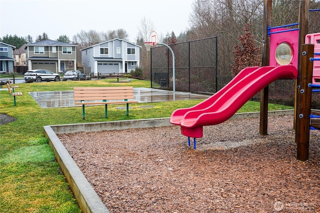 communal playground with community basketball court, a residential view, and a lawn