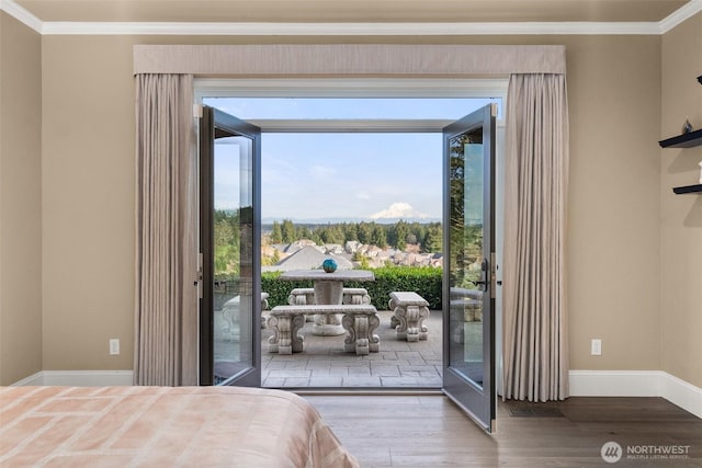 bedroom featuring access to outside, ornamental molding, and wood finished floors