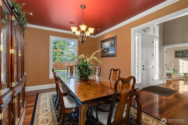 dining area featuring crown molding, baseboards, dark wood-type flooring, and a notable chandelier