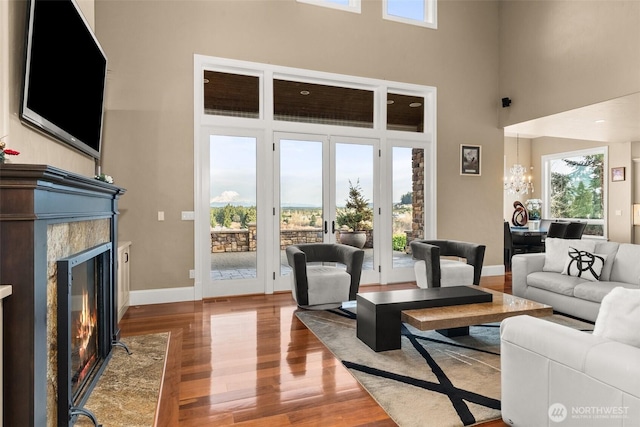 living area with a high ceiling, a premium fireplace, wood finished floors, and baseboards
