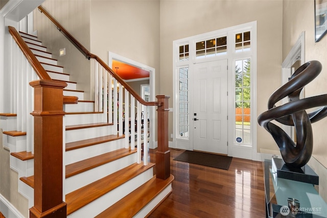 entryway with stairs, baseboards, a high ceiling, and wood finished floors