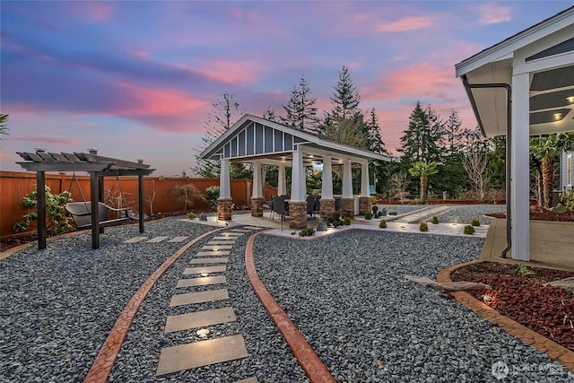 yard at dusk featuring a gazebo, a patio, a fenced backyard, and a pergola
