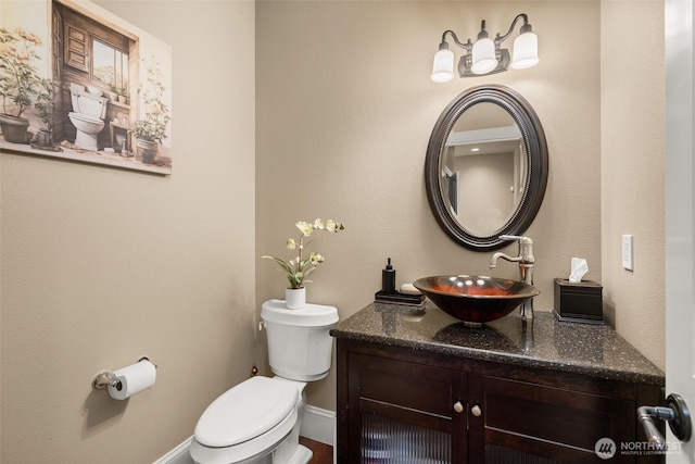 bathroom featuring toilet, baseboards, and vanity