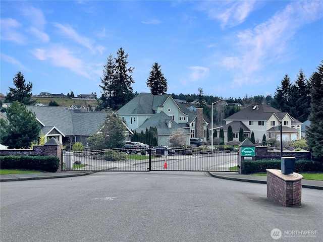 view of road with a residential view, curbs, a gate, sidewalks, and street lights