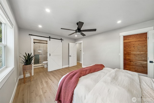 bedroom featuring recessed lighting, a barn door, ensuite bath, light wood-type flooring, and baseboards