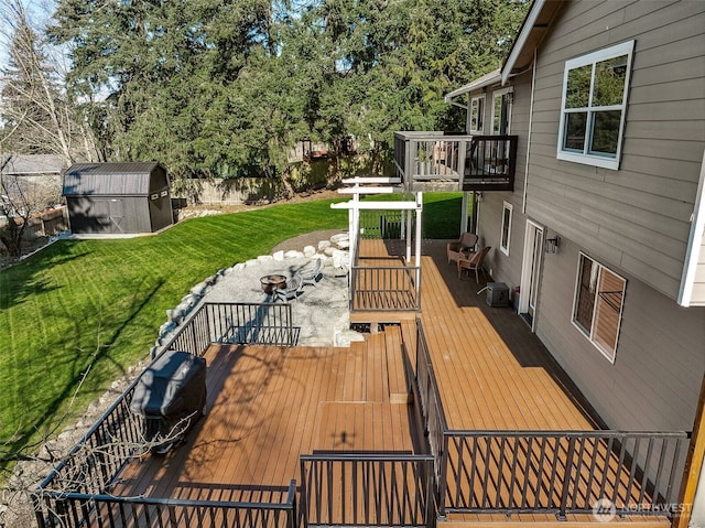 deck with a shed, an outbuilding, a fenced backyard, and a yard