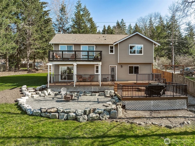 back of property featuring a yard, an outdoor fire pit, fence, and a wooden deck