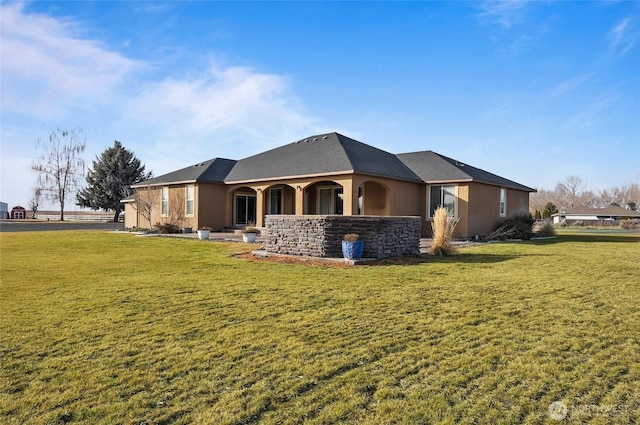 back of property with stone siding, stucco siding, and a yard