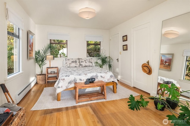 living area featuring baseboards, plenty of natural light, light wood-style flooring, and baseboard heating