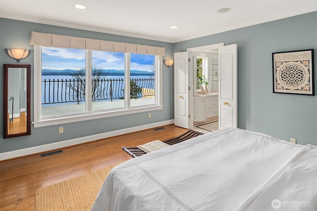 bedroom with crown molding, wood finished floors, visible vents, and baseboards