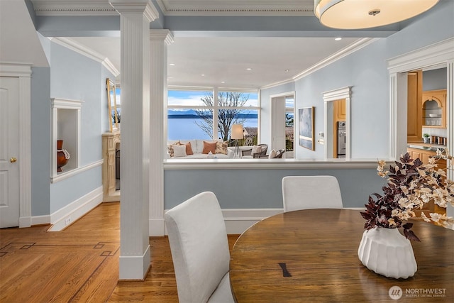 dining space featuring ornate columns, light wood-style flooring, ornamental molding, and baseboards