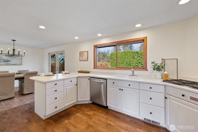 kitchen featuring white cabinets, a peninsula, light countertops, stainless steel dishwasher, and a sink