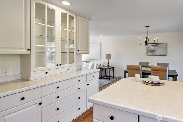 kitchen featuring decorative light fixtures, recessed lighting, light countertops, glass insert cabinets, and a chandelier