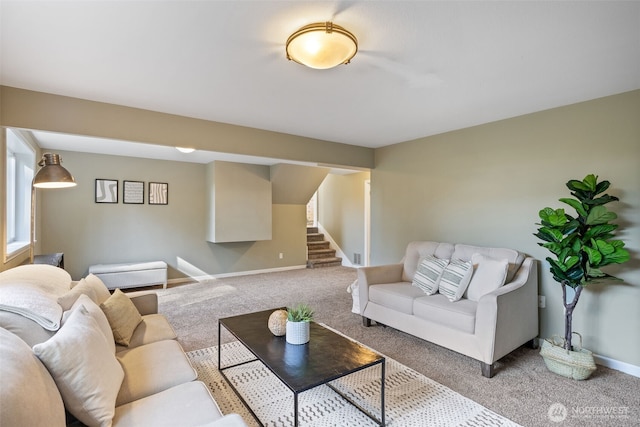 carpeted living area with stairs and baseboards