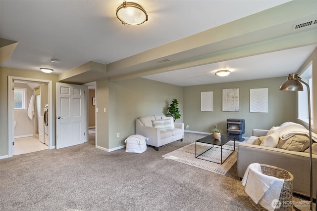 living room with a wood stove, carpet, visible vents, and baseboards