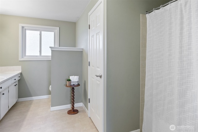 bathroom featuring a shower with curtain, toilet, vanity, and baseboards