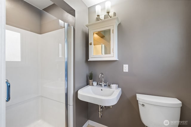 bathroom with toilet, a shower stall, and a sink