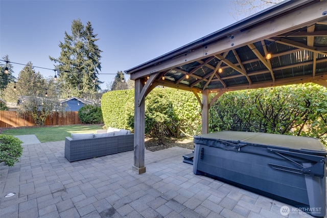 view of patio featuring fence, a hot tub, a gazebo, and an outdoor hangout area