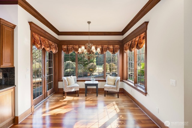 living area featuring a healthy amount of sunlight, an inviting chandelier, crown molding, and wood finished floors