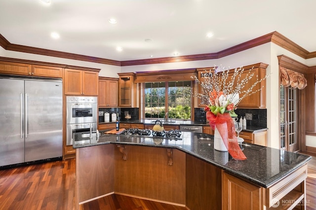 kitchen with brown cabinets, tasteful backsplash, stainless steel appliances, and dark wood-style flooring