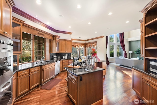 kitchen with a center island with sink, a sink, stainless steel oven, and dishwashing machine