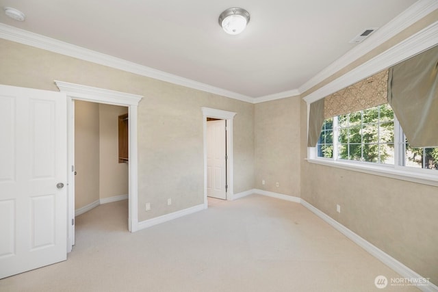 carpeted empty room with baseboards, visible vents, and crown molding