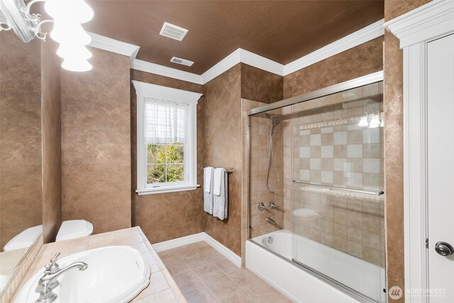 full bathroom featuring visible vents, bath / shower combo with glass door, tile patterned floors, crown molding, and a sink