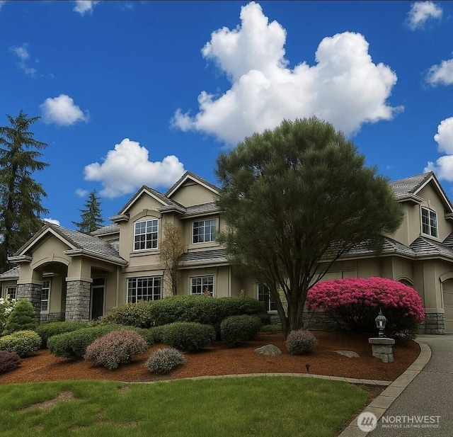 view of front of house featuring a tiled roof, stone siding, and stucco siding