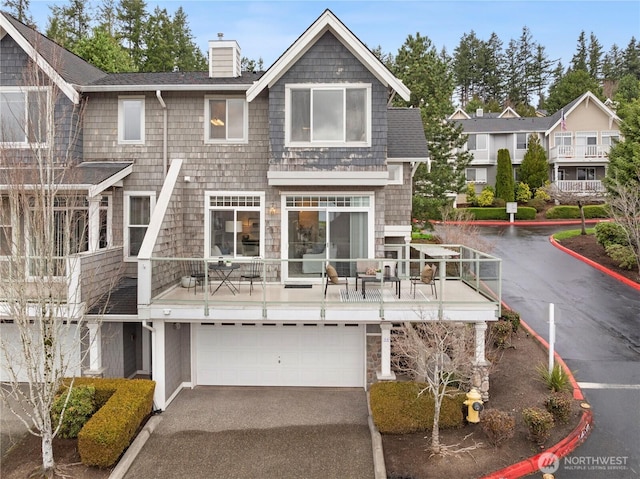 exterior space featuring driveway, an attached garage, and a chimney