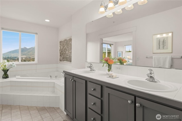 bathroom featuring recessed lighting, double vanity, a sink, and a bath