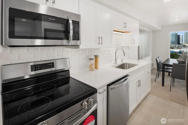 kitchen featuring a sink, white cabinetry, light countertops, appliances with stainless steel finishes, and tasteful backsplash