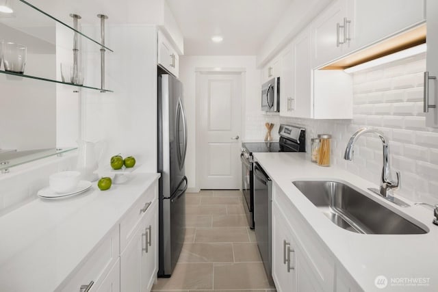 kitchen featuring white cabinets, appliances with stainless steel finishes, backsplash, and a sink