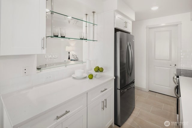 kitchen with light countertops, appliances with stainless steel finishes, white cabinetry, and decorative backsplash