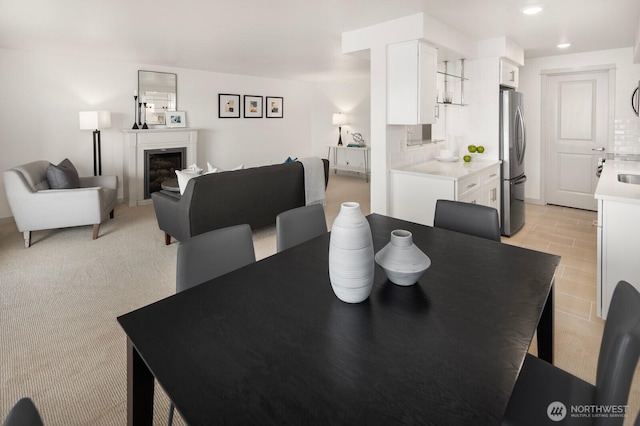 dining room with recessed lighting, light carpet, and a fireplace