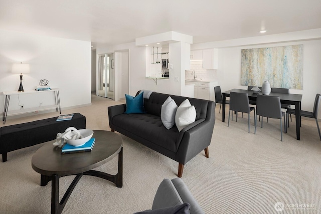 living room with baseboards and light colored carpet