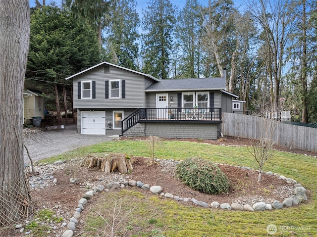 tri-level home featuring a garage, fence, stairs, driveway, and a front lawn