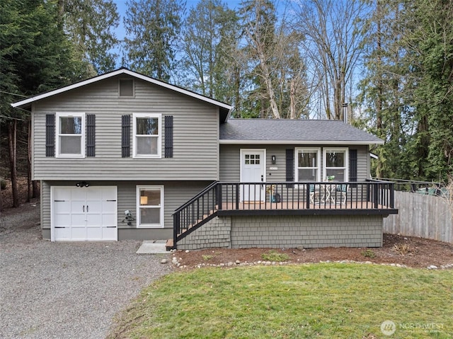 tri-level home with gravel driveway, stairway, an attached garage, fence, and a front lawn