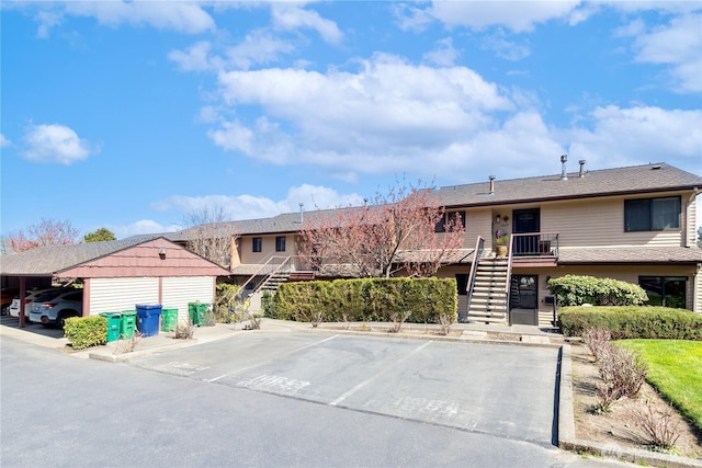 view of property featuring uncovered parking and stairway