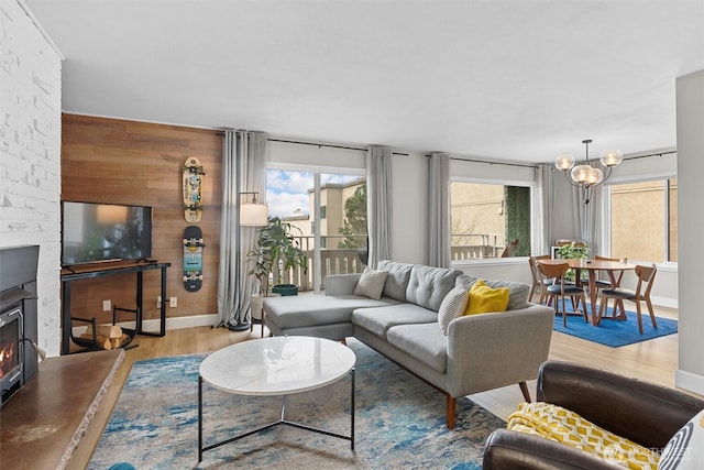 living room featuring a chandelier, a fireplace, wood finished floors, and baseboards