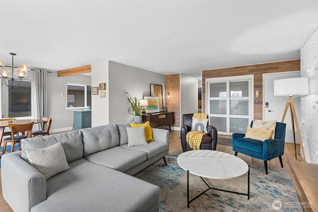 living room with baseboards, a chandelier, and wood finished floors