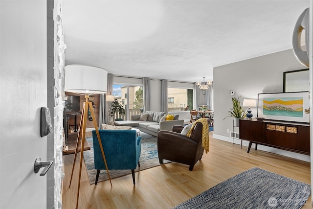 living room with a notable chandelier, baseboards, and wood finished floors