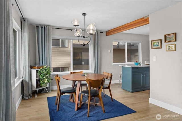 dining room featuring light wood-style flooring, beam ceiling, baseboards, and a notable chandelier