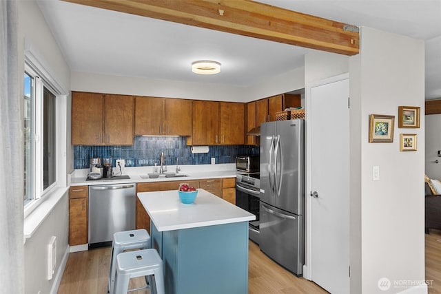 kitchen with brown cabinetry, light wood-style floors, stainless steel appliances, and a sink