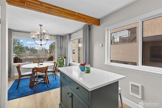 kitchen with a center island, light countertops, light wood-type flooring, a chandelier, and beam ceiling