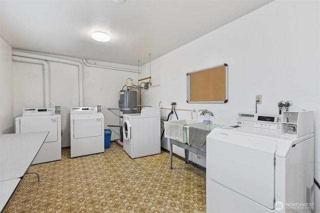 common laundry area with washing machine and dryer, water heater, a sink, and light floors