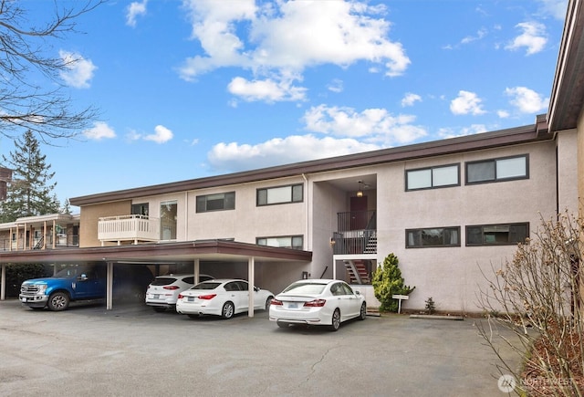 view of property with covered parking and stairway