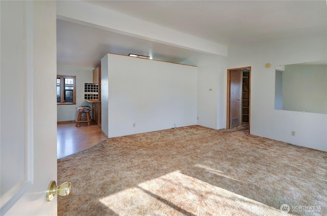 carpeted empty room featuring vaulted ceiling with beams and visible vents